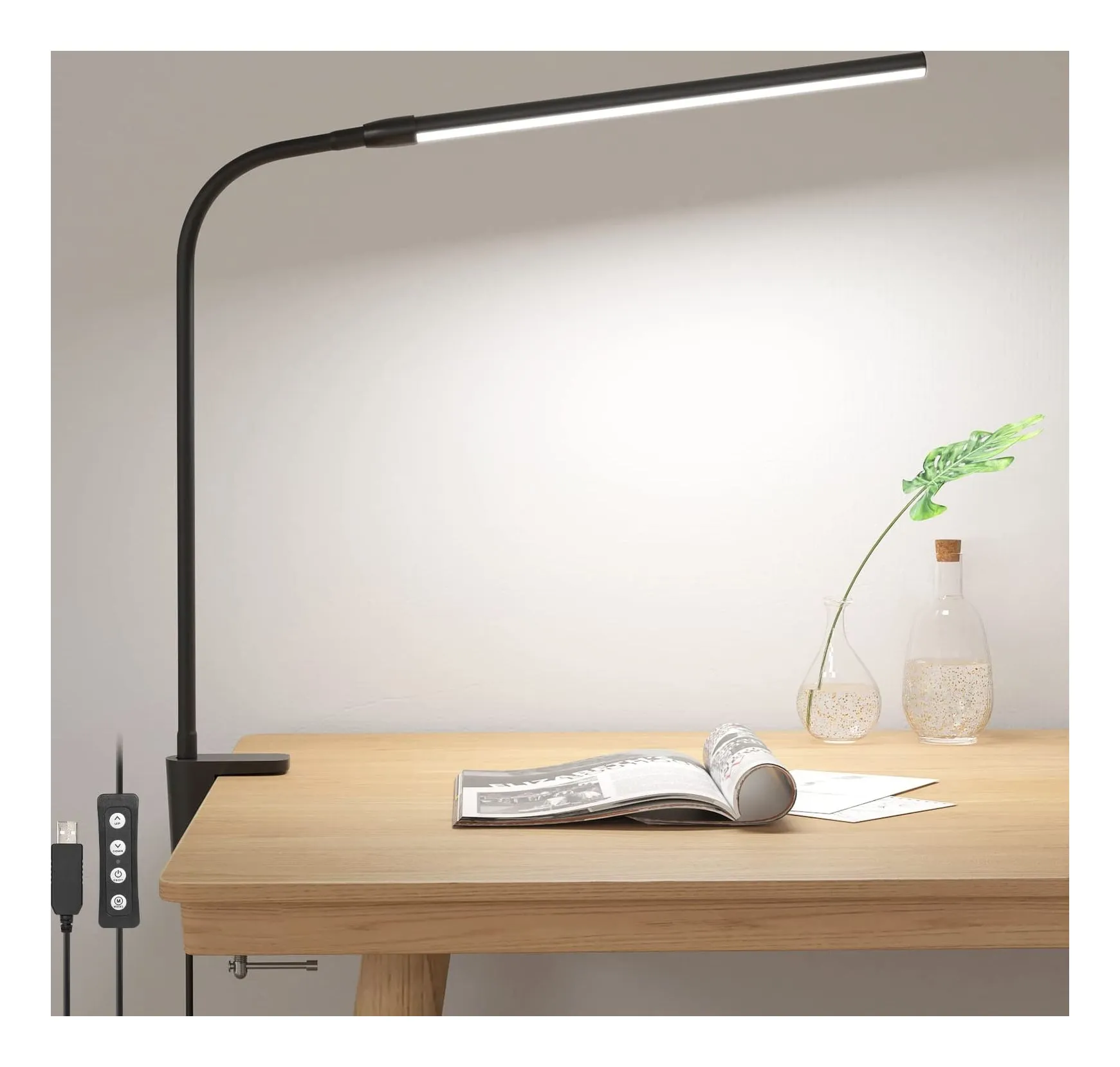 Lepro clamp desk lamp in black: a gooseneck arm rising from a C-clamp on the edge of a wooden desk, lighting an open magazine, with the in-line USB switch hanging below